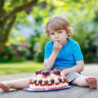 garotinho comemorando aniversário com bolo grande foto