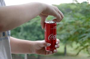 carcóvia. ucrânia - 2 de maio de 2019 mulher caucasiana segura lata vermelha de coca-cola com fundo verde do jardim foto