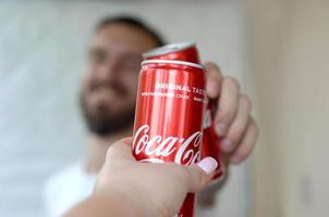 carcóvia. ucrânia - 2 de maio de 2019 jovem feliz levanta lata de coca-cola com amiga no interior da garagem foto