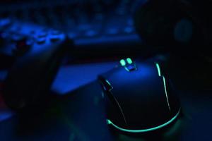 gamepad moderno e mouse para jogos encontra-se com teclado e fones de ouvido na mesa na cena da sala de jogos escura. conceito de jogo em equipe cooperativo foto