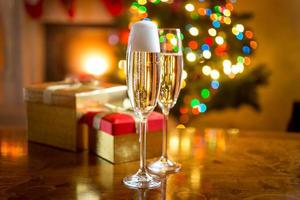 duas taças de champanhe contra lareira decoradas para o natal foto