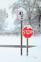 Pare. sinal de estrada vermelho está localizado na auto-estrada cruzando a linha férrea na temporada de inverno foto