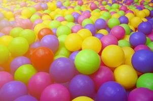 muitas bolas de plástico coloridas em uma piscina infantil em um playground. padrão de close-up foto