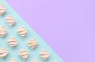 marshmallow colorido disposto em fundo de papel violeta e azul. padrão texturizado criativo pastel. mínimo foto