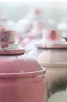 um monte de latas de aerossol sujas e usadas de tinta rosa brilhante. fotografia macro com profundidade de campo rasa. foco seletivo no bico de pulverização foto
