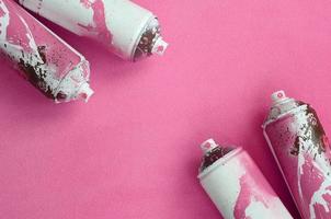 algumas latas de spray de aerossol rosa usadas com gotas de tinta estão em um cobertor de tecido de lã rosa claro macio e peludo. cor de design feminino clássico. conceito de vandalismo de graffiti foto
