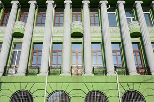 restaurado antigo edifício de vários andares com colunas antigas, pintado em verde foto