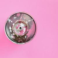 lata de spray usada com pingos de tinta rosa está no fundo de textura do papel de cor rosa pastel de moda em conceito mínimo foto