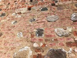 a textura da antiga parede de tijolos rachados de pedra antiga medieval antiga de pedra rachada de tijolos retangulares de barro vermelho e grandes pedras, paralelepípedos. o fundo foto