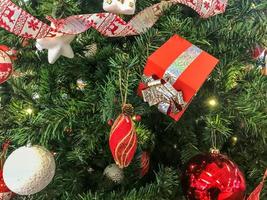 festivas multicoloridas lindas bolas de fantasia brilhantes, brinquedos, caixas de presente, decorações na árvore de natal verde com agulhas e galhos para o ano novo. fundo, textura foto