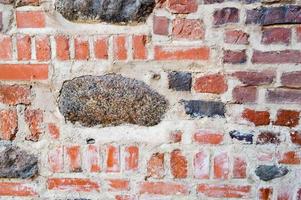 a textura da antiga parede de tijolos rachados de pedra antiga medieval antiga de pedra rachada de tijolos retangulares de barro vermelho e grandes pedras, paralelepípedos. o fundo foto