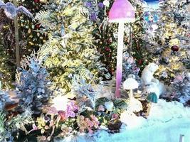 decorações fofas de ano novo para o shopping center. árvores de natal artificiais com iluminação. abeto coberto com neve artificial. ao lado de um cogumelo rosa com uma tampa redonda foto