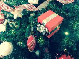 festivas multicoloridas lindas bolas de fantasia brilhantes, brinquedos, caixas de presente, decorações na árvore de natal verde com agulhas e galhos para o ano novo. fundo, textura foto