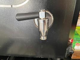torneiras e tubos de metal brilhantes para servir café de uma máquina de café. aparelho para bebidas quentes foto