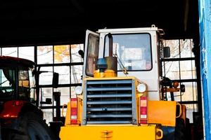 grande trator amarelo poderoso com rodas grandes no hangar, armazém, garagem com portões abertos foto