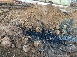 um monte de areia empilhado em um canteiro de obras. óleo combustível preto e viscoso é derramado no chão. materiais de construção para a construção de novas casas. pedras e detritos na areia foto