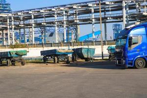 grande caminhão azul com táxi e reboque na planta industrial no fundo das tubulações, loja de transporte foto