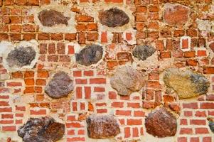 a textura da antiga parede de tijolos rachados de pedra antiga medieval antiga de pedra rachada de tijolos retangulares de barro vermelho e grandes pedras, paralelepípedos. o fundo foto