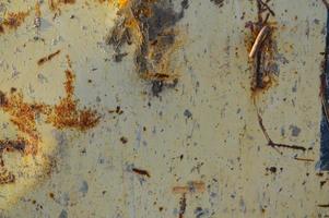enferrujado, amarelo com textura de buracos. um pedaço de metal enferrujado com corrosão, a pintura rachada pela velhice e precipitação. no centro há recortes de danos foto