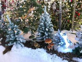 decorações fofas de ano novo para o shopping center. árvores de natal artificiais com iluminação. pássaros estão sentados nos abetos. decoração de vitrine diy foto