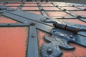 textura de uma antiga porta de metal de ferro resistente vermelho medieval antigo antigo com padrões de rebites e pregos. o fundo foto