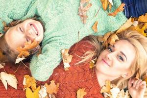 menina e mãe deitada nas folhas de outono foto