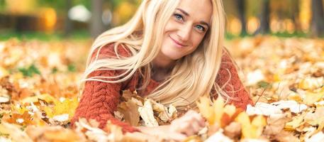 mulher deita-se em folhas no parque outono foto