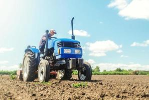 o agricultor trabalha em um trator. afrouxando a superfície, cultivando a terra para plantar mais. triturando e soltando o solo, removendo as raízes das plantas da última colheita. equipamentos de tecnologia de cultivo. foto