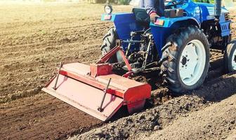 agricultor em um trator cultiva a terra após a colheita. desenvolvimento de tecnologias agrícolas. moer afrouxar arar o solo em ruínas para novas semeaduras por plantas cultivadas. fresadora foto