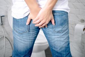 homem tem diarréia segurando a bunda no banheiro. foto