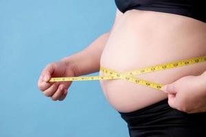 retrato de uma mulher com excesso de peso medindo sua gordura da barriga foto