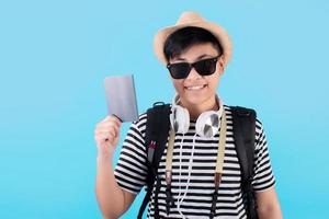 turistas asiáticos sorrindo alegremente segurando seus passaportes e aproveitando as férias em um fundo azul. foto