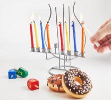 fundo de hanukkah feriado judaico. prato tradicional é rosquinhas doces. candelabro de configuração de mesa de hanukkah com velas e piões em fundo branco. acender velas de chanuká. espaço de cópia foto