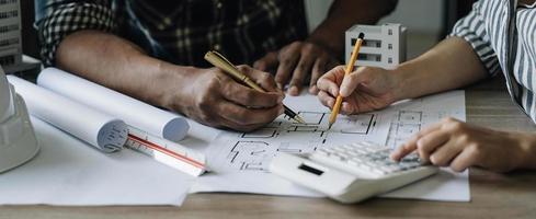 engenheiros de construção de equipe trabalhando no canteiro de obras com planta na mesa foto