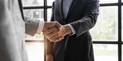 empresários apertando as mãos, terminando a reunião, etiqueta empresarial, parabéns, conceito de fusão e aquisição foto