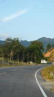 a bela vista do campo com a estrada e as montanhas como pano de fundo foto