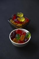 marmelada de geléia ursos em um copo de cerâmica em um fundo preto. close-up de doces coloridos de marmelada. textura de fundo. foto