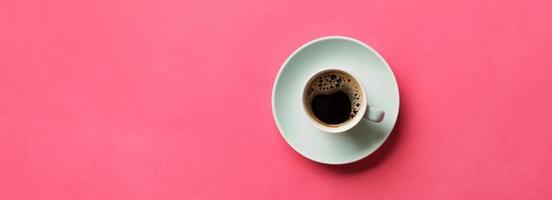 xícara de café azul em um fundo rosa colorido. vista superior com espaço de cópia. conceito de manhã. bandeira foto