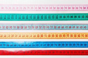 close-up de um grupo de fitas métrica coloridas deitado em linhas como pano de fundo. conceito de dieta em fundo de madeira foto