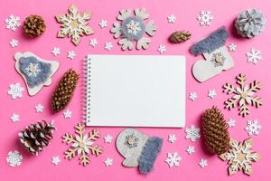 vista superior do notebook, brinquedos de férias e decorações em fundo rosa de natal. conceito de tempo de ano novo foto