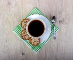 xícara de café com pilha de vários biscoitos amanteigados e aveia com cereais em fundo de madeira. foto