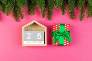 vista superior do calendário de madeira, caixa de presente e abeto em fundo colorido. dia vinte e cinco de dezembro. tempo de natal com espaço de cópia foto