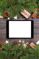 tablet digital simulado com decorações rústicas de fundo de madeira de natal para apresentação de aplicativos. vista superior com espaço de cópia foto