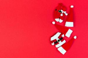 vista superior de chapéus de Papai Noel vermelhos e roupas em fundo colorido. feliz natal conceito com espaço de cópia foto