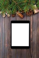 tablet digital simulado com decorações rústicas de fundo de madeira de natal para apresentação de aplicativos. vista superior com espaço de cópia foto