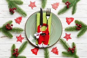 vista superior do jantar de natal em fundo de madeira. prato, utensílio, abeto e decorações de férias. conceito de tempo de ano novo foto