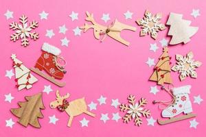 vista superior do fundo rosa decorado com brinquedos festivos e renas de símbolos de natal e árvores de ano novo. conceito de férias com espaço de cópia foto