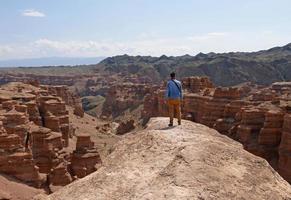 homem de camisa jeans com vista para charyn canyon no cazaquistão foto