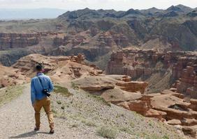 homem de camisa jeans com vista para charyn canyon no cazaquistão foto