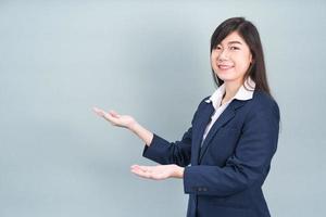 mulher asiática em gestos de palma de mão aberta de terno com espaço vazio foto